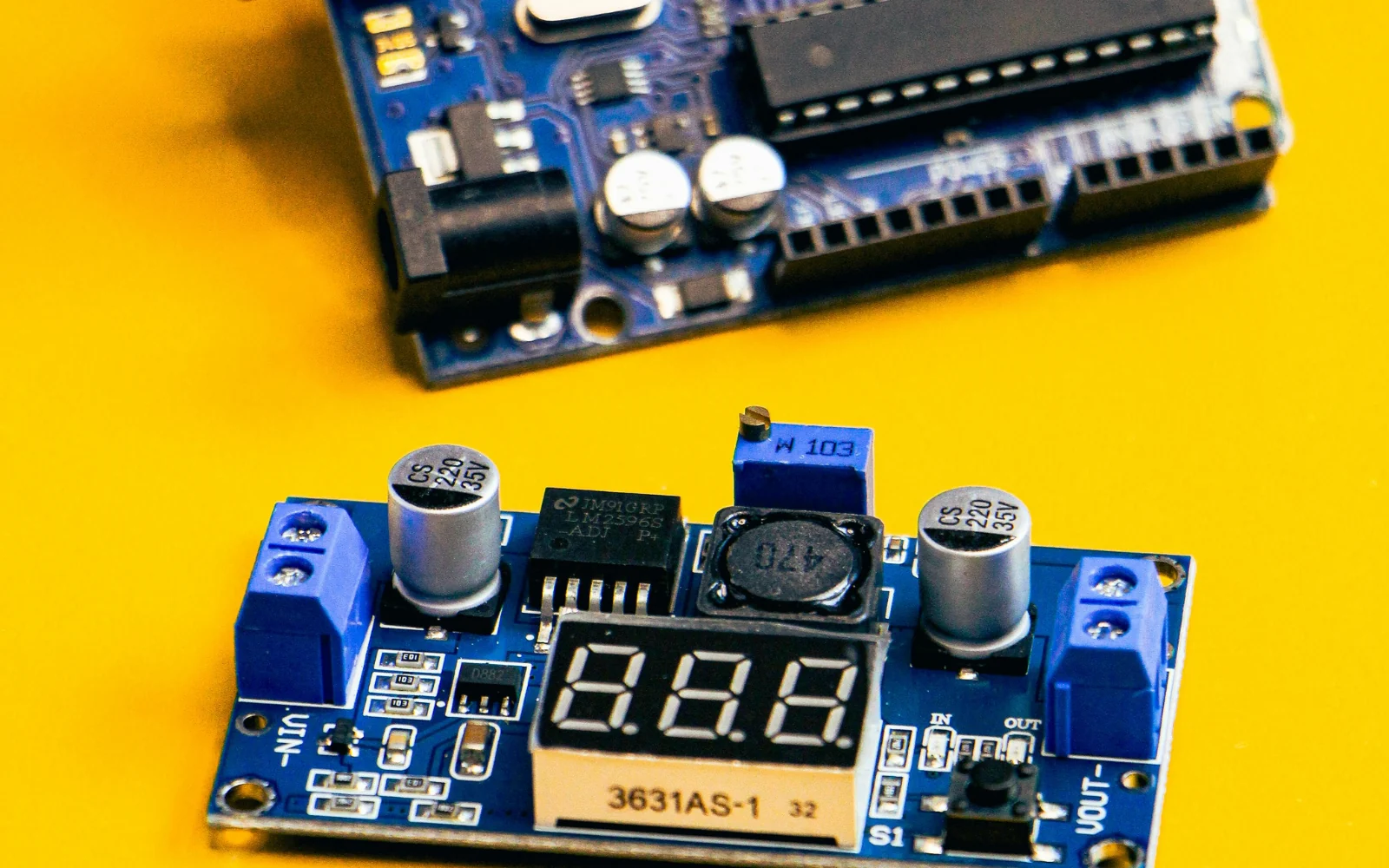 Microcontroller development board and sensor module on a yellow surface
