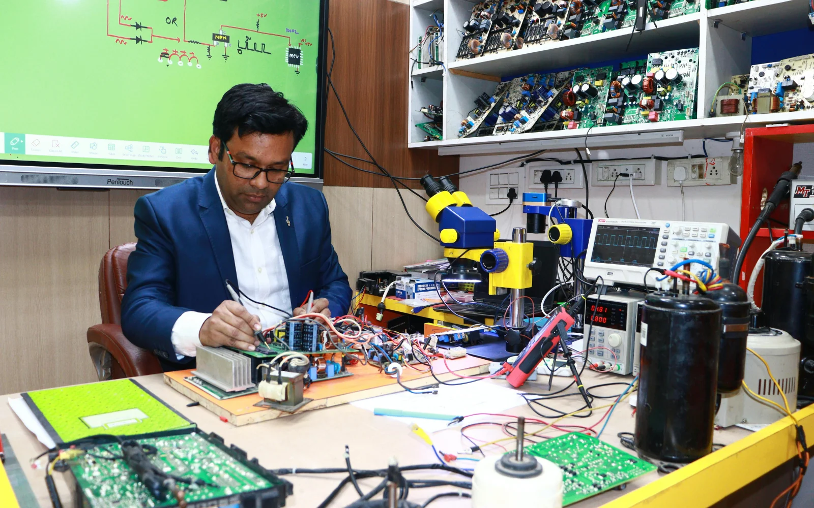 Electronics technician working with instruments and circuit boards at a bench