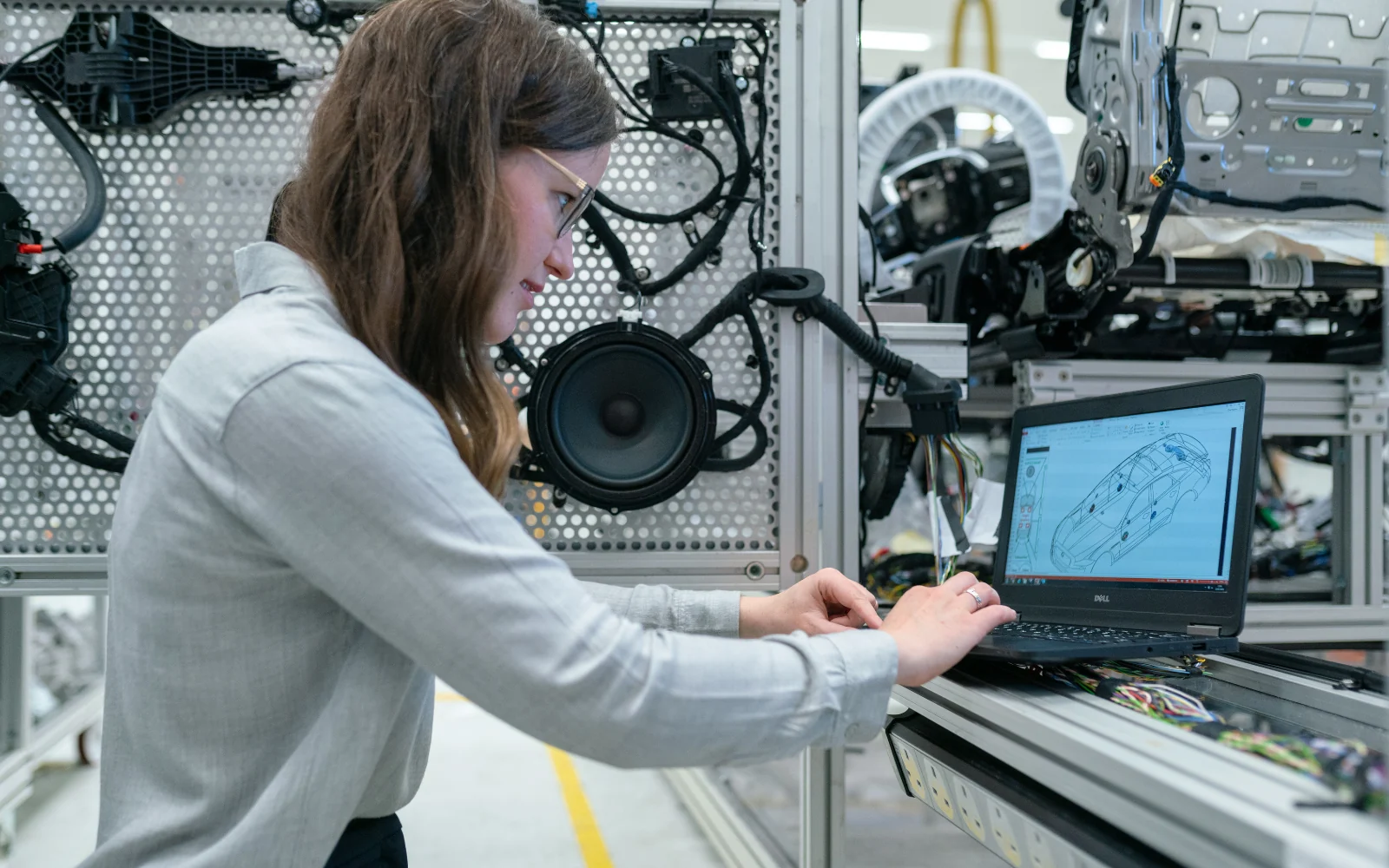 Engineer using a laptop beside electronic equipment in a workshop