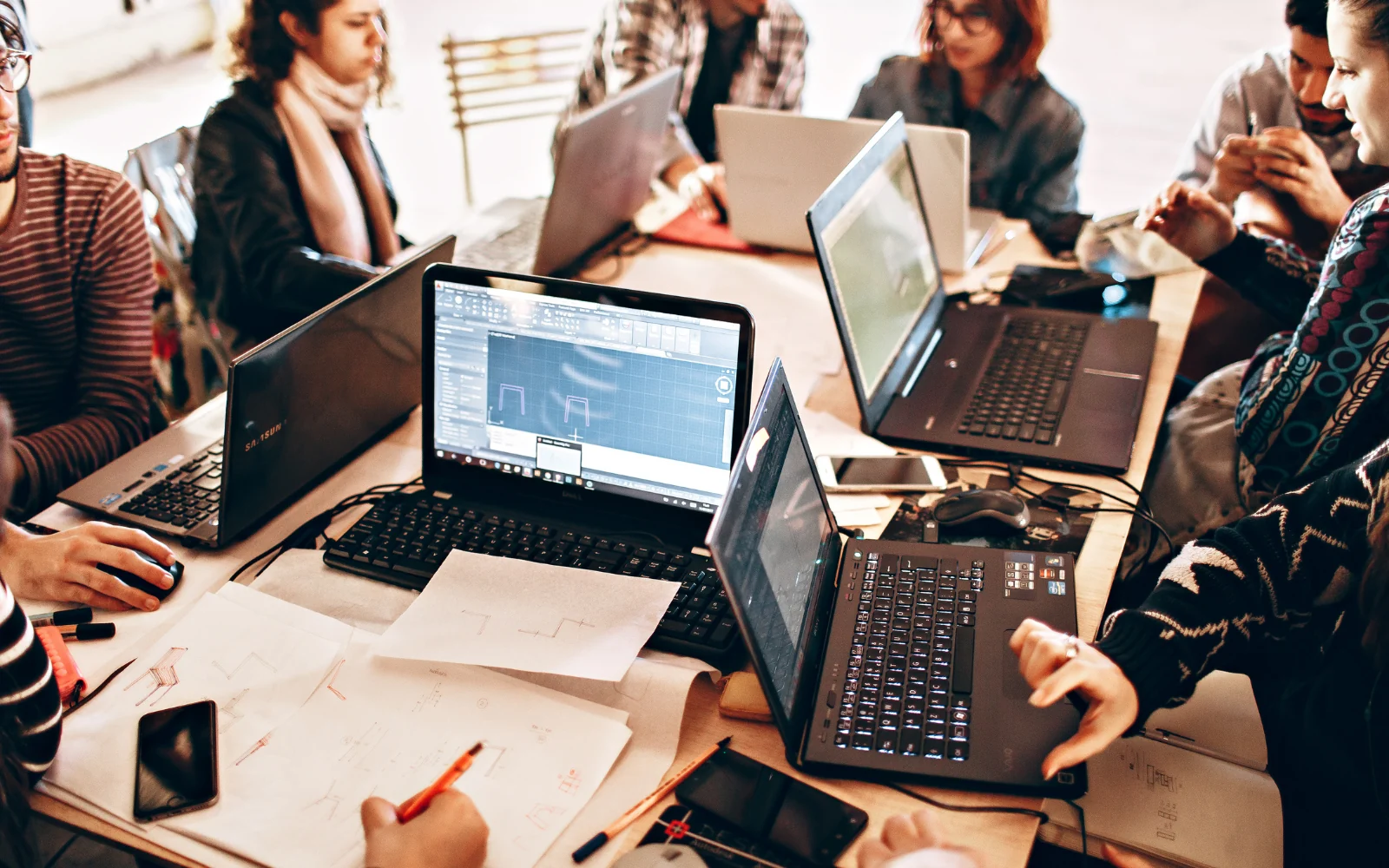 Colleagues reviewing software on laptops around a shared table