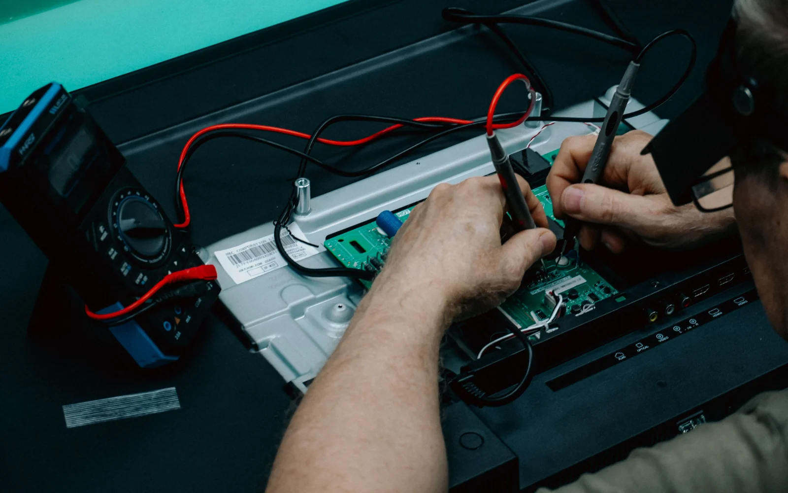 Technician using measurement probes on an electronic circuit board