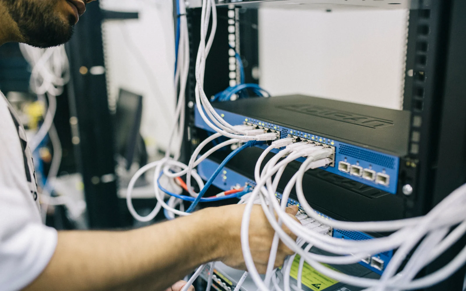 Engineer connecting network cables to rack-mounted equipment