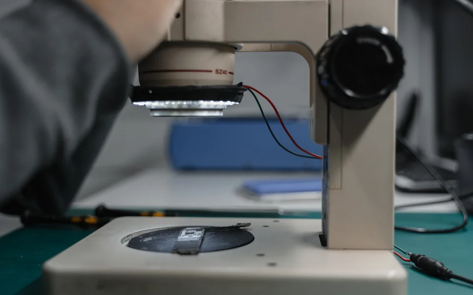 Electronics board positioned beneath an illuminated inspection microscope