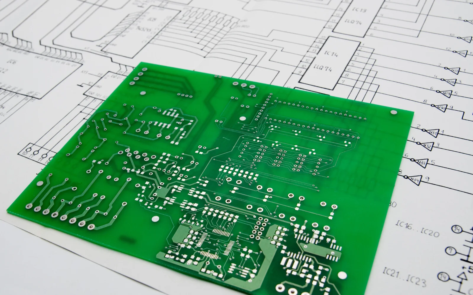 Green circuit board on top of engineering drawings